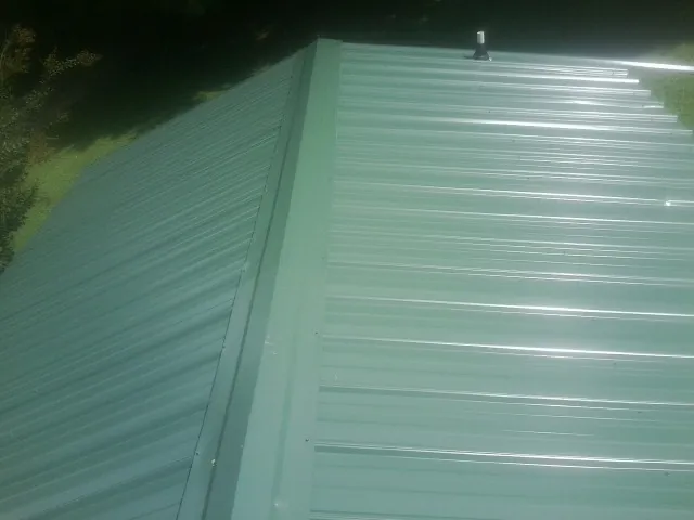 New green metal panels meeting at the ridge of a roof — Flat Roof Repair work by our crew in Nottingham
