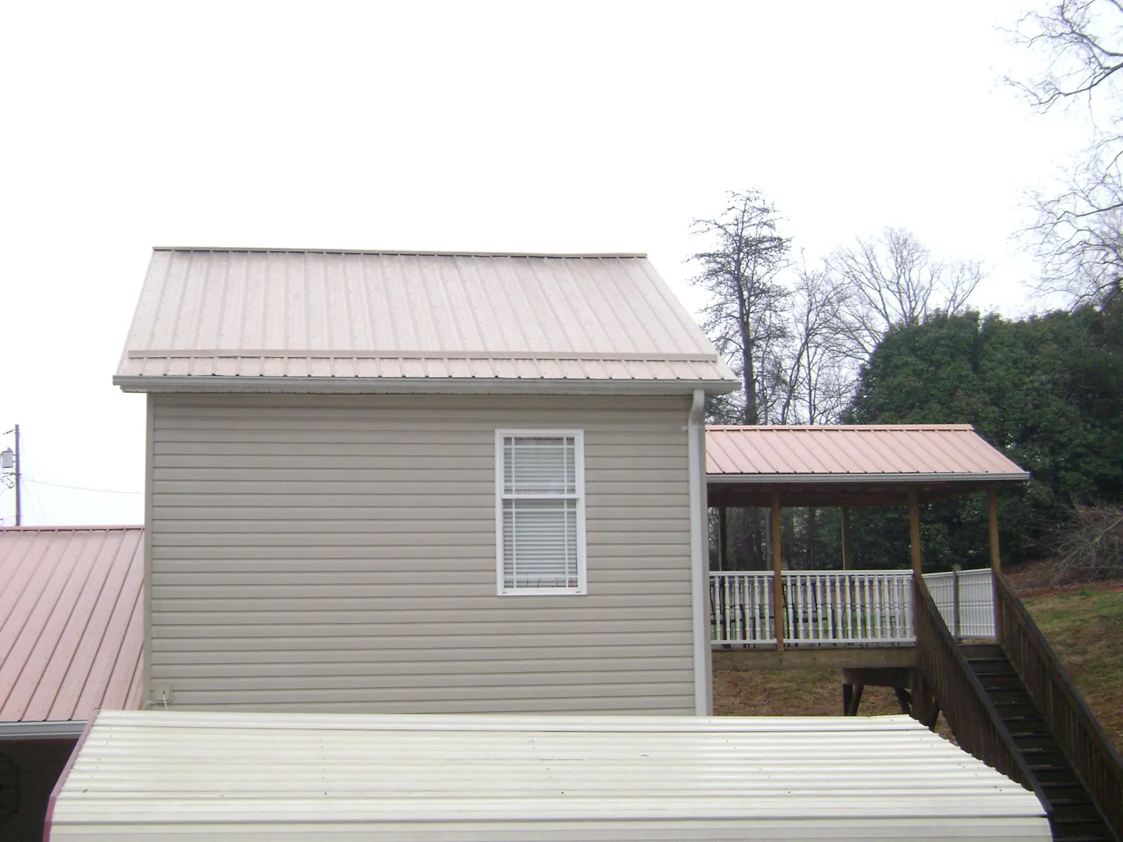 Tan metal roofs on a two story addition and attached porch, from a Roof Replacement job in Nottingham