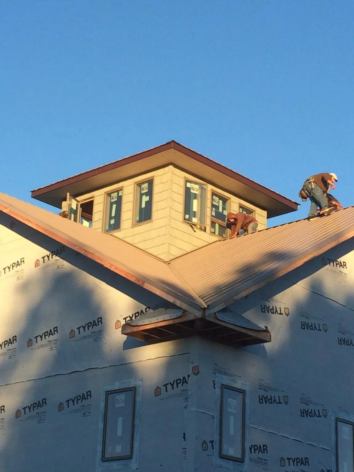 Roofers working around a rooftop cupola on a new metal roof at sunset — Roof Waterproofing in Nottingham by Roofing Brothers